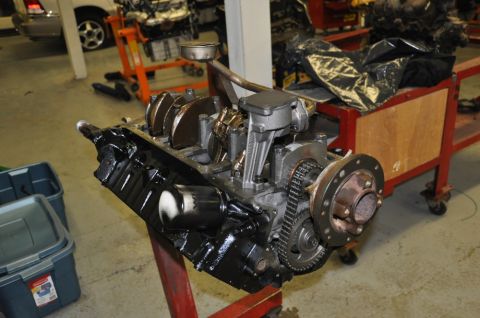 1996 Ford Bronco - Engine block assembly with crankshaft, pistons, and timing chain, mounted on a red stand in a workshop.