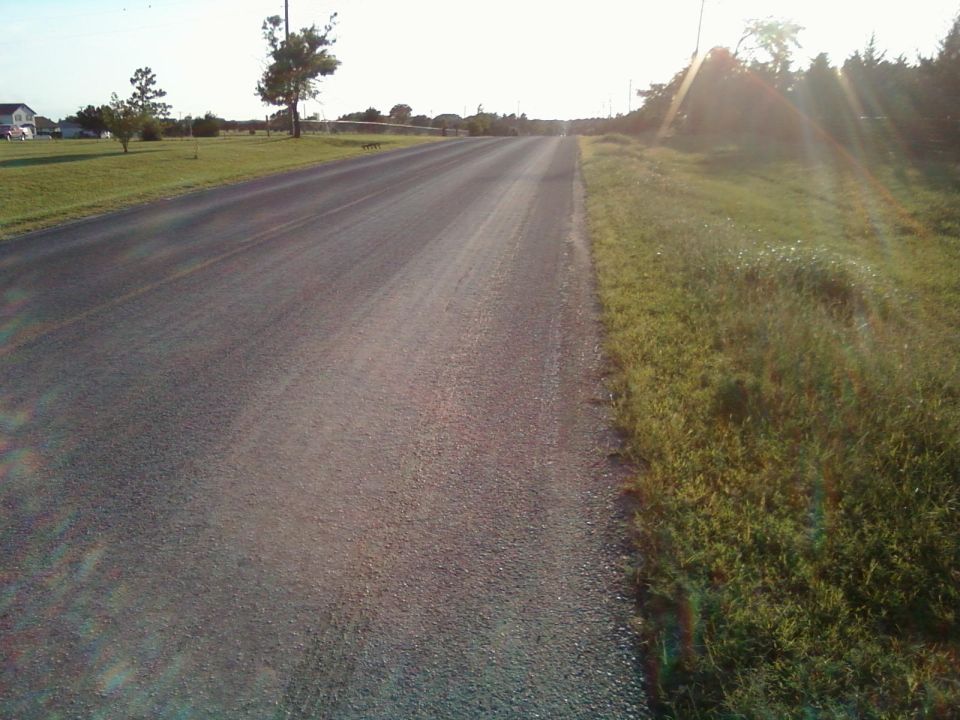 empty two-lane road in a rural area with grass and trees on the side