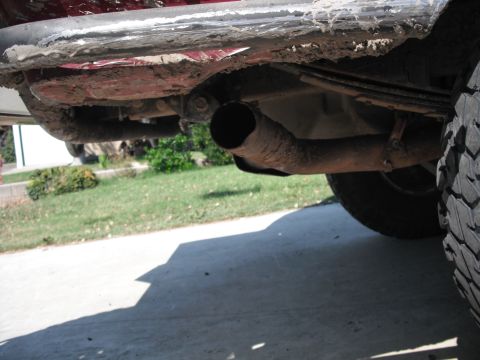 1991 Ford Bronco - The underside of a vehicle shows mud accumulation and a worn exhaust system.
