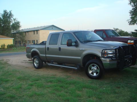 1992 Ford Bronco - Gray Ford F-250 Super Duty crew cab pickup truck parked outside with a red truck in the background.