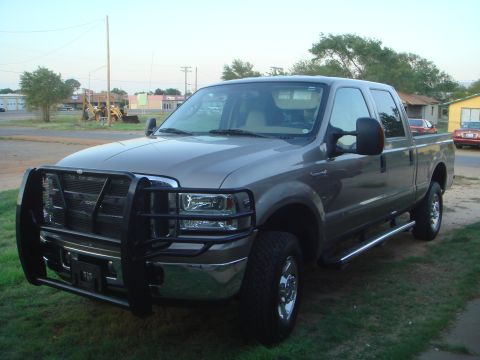 1992 Ford Bronco - This Ford F-250 Super Duty pickup truck is parked on a grassy area with buildings in the background.