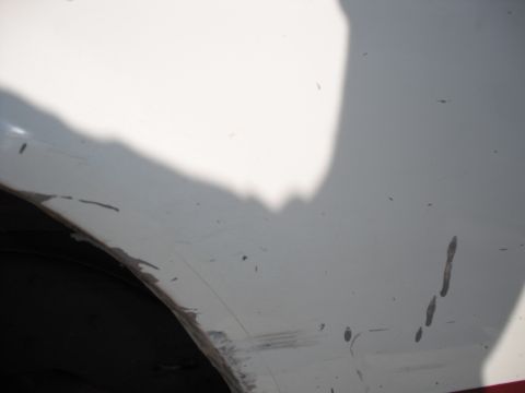 1991 Ford Bronco - Close-up view of a white vehicle's fender and tire, showing signs of wear and dirt.