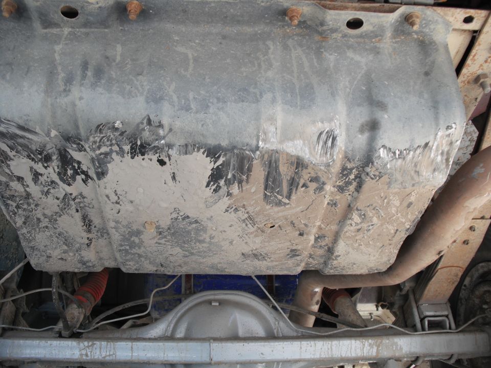 Undercarriage view of a dirty fuel tank and exhaust system