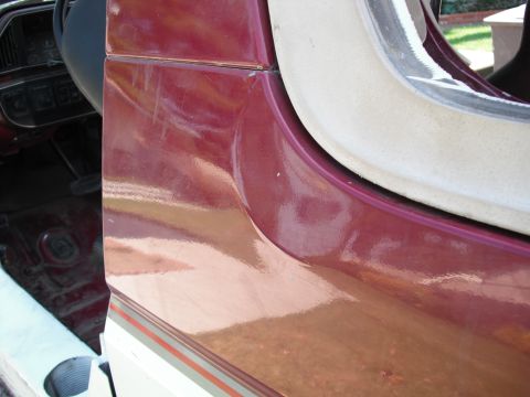 1991 Ford Bronco - Close-up of a 1991 Ford Bronco's maroon door jamb and interior floor, revealing scuff marks and the gas pedal.