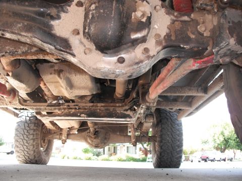 1991 Ford Bronco - The underside of a vehicle reveals its complex mechanical components and heavy-duty suspension system.