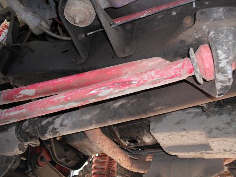 1991 Ford Bronco - Close-up view of the undercarriage, highlighting red suspension parts and various mechanical components.