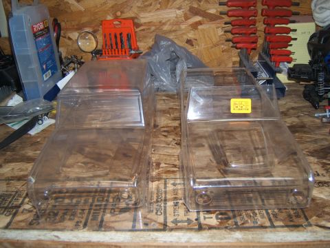 1988 Ford Bronco - Two unpainted RC car bodies are displayed on a workbench, ready for customization.