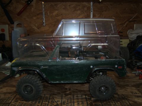 1988 Ford Bronco - RC crawler body with clear top, side view, on a wooden surface.