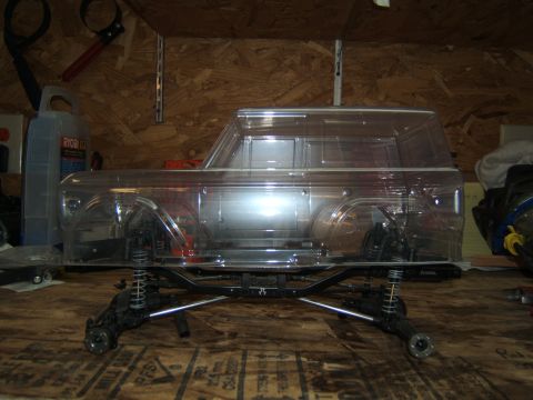 1988 Ford Bronco - Unpainted clear plastic body for an RC crawler sits on its chassis, awaiting customization.