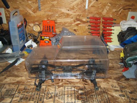 1988 Ford Bronco - RC crawler chassis with clear body shell, sitting on a workbench with tools.