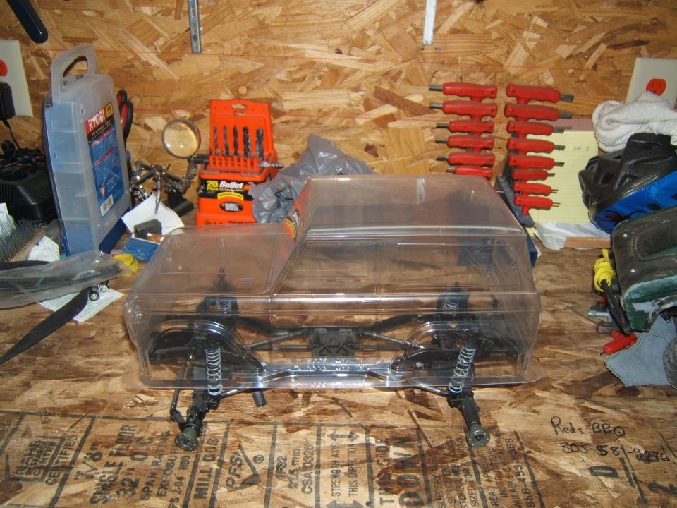 RC crawler chassis with clear plastic body shell, showing suspension and frame