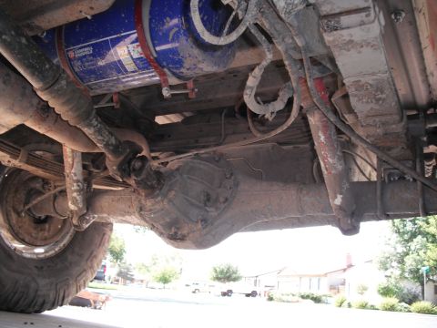 1991 Ford Bronco - Undercarriage components including a driveshaft, differential, and a large blue tank are visible.