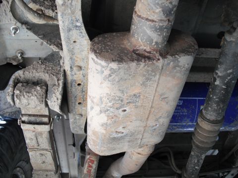 1991 Ford Bronco - The underside of a vehicle shows the exhaust system and a blue filter, with visible mud and rust.