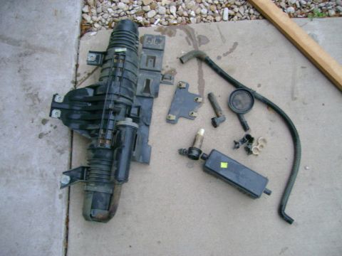 2007 Ford Mustang - Various engine parts, including an air intake manifold and hoses, are spread out on a concrete surface.