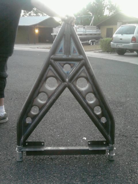 1995 Ford Bronco - Custom metal A-frame part, likely for off-road vehicle suspension, held by a person.