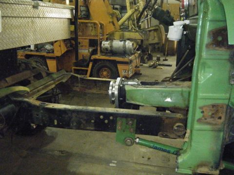 1978 Ford Bronco - Close-up of vehicle frame and suspension parts with industrial equipment in the background.