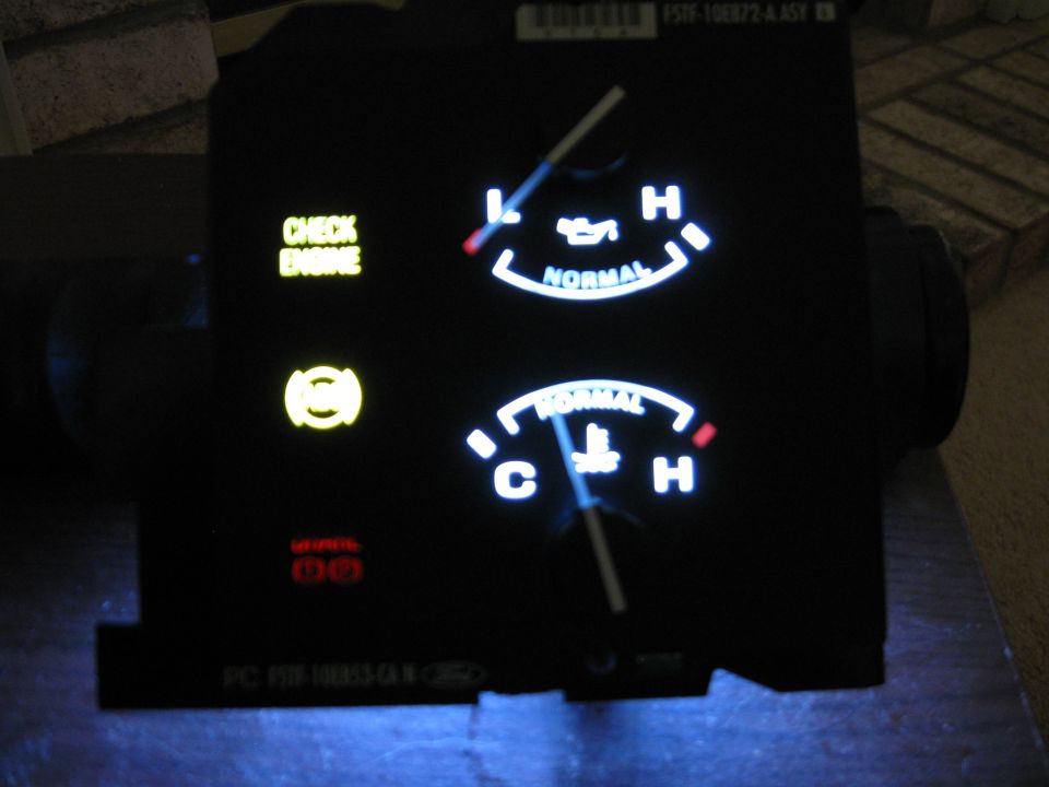 Instrument cluster with oil pressure and temperature gauges, check engine light, and brake warning light illuminated