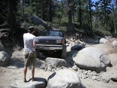 1991 Ford Bronco - Ford Bronco navigating a challenging off-road trail with large boulders.