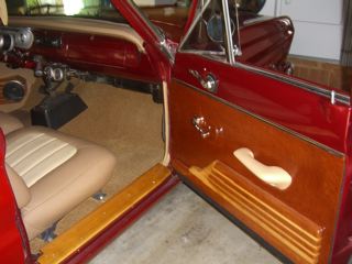 1964 Ford Falcon - Interior view of a red car with tan seats and wood paneling on the door. Watermark present.