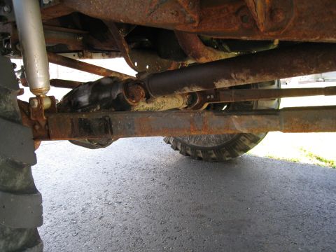 1996 Ford Bronco - Close-up of a vehicle's rusty undercarriage, showing suspension and driveshaft components.