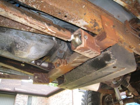 1996 Ford Bronco - The heavily rusted undercarriage of a vehicle shows significant wear and tear on its frame and suspension parts.
