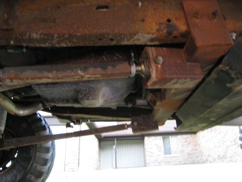 1996 Ford Bronco - The underside of a vehicle reveals significant rust and worn components, with a partial view of a tire.