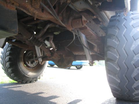 1996 Ford Bronco - The underside of a vehicle is shown, focusing on the rear axle, suspension components, and a large tire.