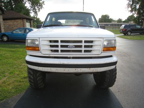 1996 Ford Bronco - Front view of a white Ford Bronco with aftermarket tires, parked outdoors next to another vehicle.