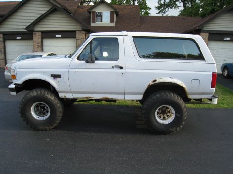 1996 Ford Bronco - This lifted Ford Bronco has a side profile view, showing its large tires and slightly rusted wheel wells.