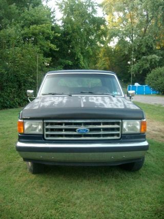 1987 Ford Bronco - Frontal view of a dark blue 1987 Ford Bronco with a chrome bumper and faded hood paint.