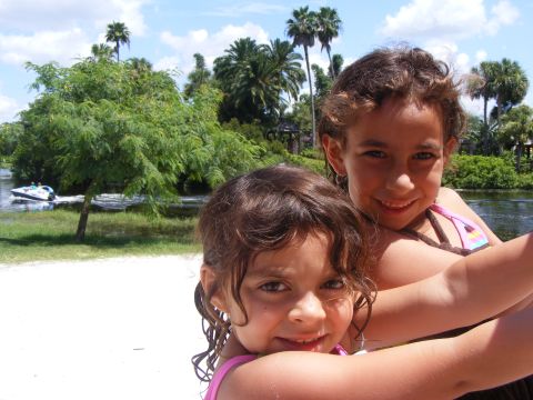 2008 Jeep Cherokee - Two smiling girls pose for a photo on a sunny day near a body of water with lush greenery.