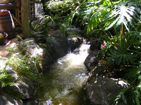 2008 Jeep Cherokee - A tranquil garden scene features a small waterfall cascading over rocks amidst dense foliage and a rustic wooden barrel.