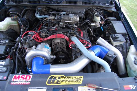 1985 Mercury Grand Marquis - The engine bay features a prominent turbocharger and aftermarket performance parts, with visible branding stickers.
