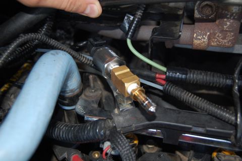 1985 Mercury Grand Marquis - Close-up view of a sensor installed in an engine bay, with a blue hose and wiring visible.