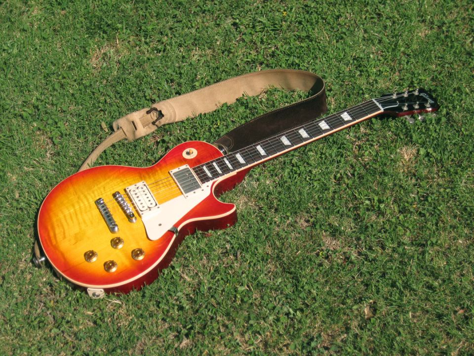 Electric guitar with sunburst finish and strap on grass