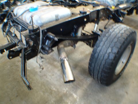 1996 Ford Bronco - Close-up view of the exhaust system and rear tire on a 1996 Ford Bronco undergoing engine rebuild.