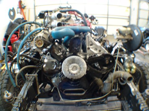 1996 Ford Bronco - The engine assembly is shown with various components and hoses connected, partially installed in a vehicle frame.