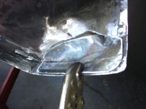 1979 Ford F-250 - Close-up of a metal panel being worked on, showing welding and a clamp. The surface is reflective and shows signs of repair.