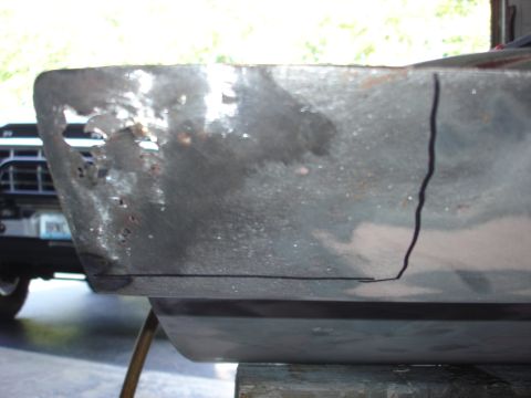 1979 Ford F-250 - Close-up of a heavily rusted metal panel with scribe lines, showing a portion of a truck grille in the background.