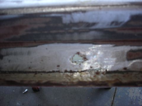 1979 Ford F-250 - Close-up of a rusted metal panel with a hole, revealing a lighter color beneath. Supermotors.net logo is visible.