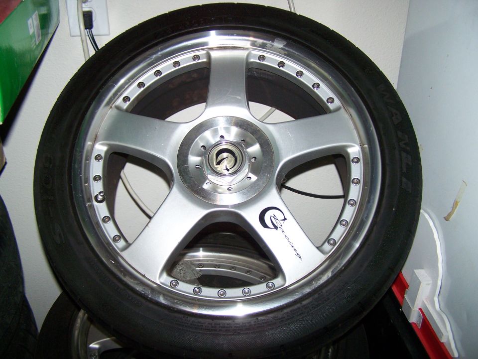 Silver five-spoke alloy wheel with a black tire, showing a "G-Racing" logo