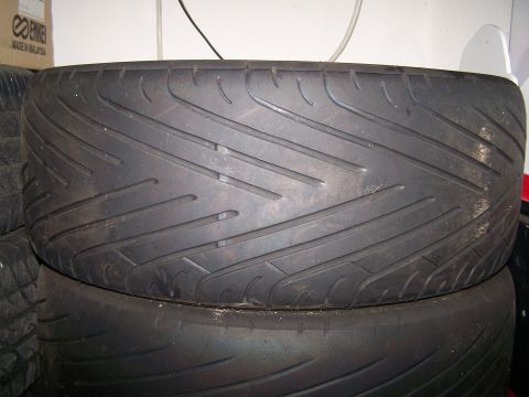 1997 Mitsubishi Eclipse - A close-up view of a tire, showing its tread pattern. A box with the Enkei logo is visible in the background.