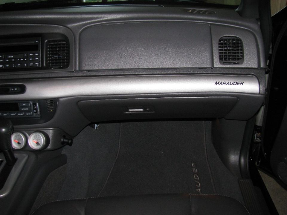 Interior shot of a 2003 Mercury Marauder dashboard, showing the glove box, air vents, and 'Marauder' badging
