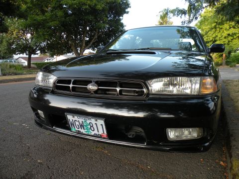 1998 Subaru Legacy - This 1998 Subaru Legacy features a distinctive chrome grille and is parked curbside on a sunny day.