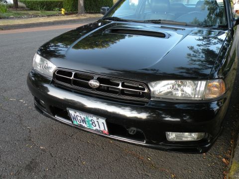 1998 Subaru Legacy - Front view of a black 1998 Subaru Legacy showing the grille and headlights.