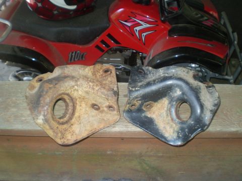 1979 Ford Bronco - Two metal brackets are shown, one heavily rusted and the other painted black, with a red ATV in the background.