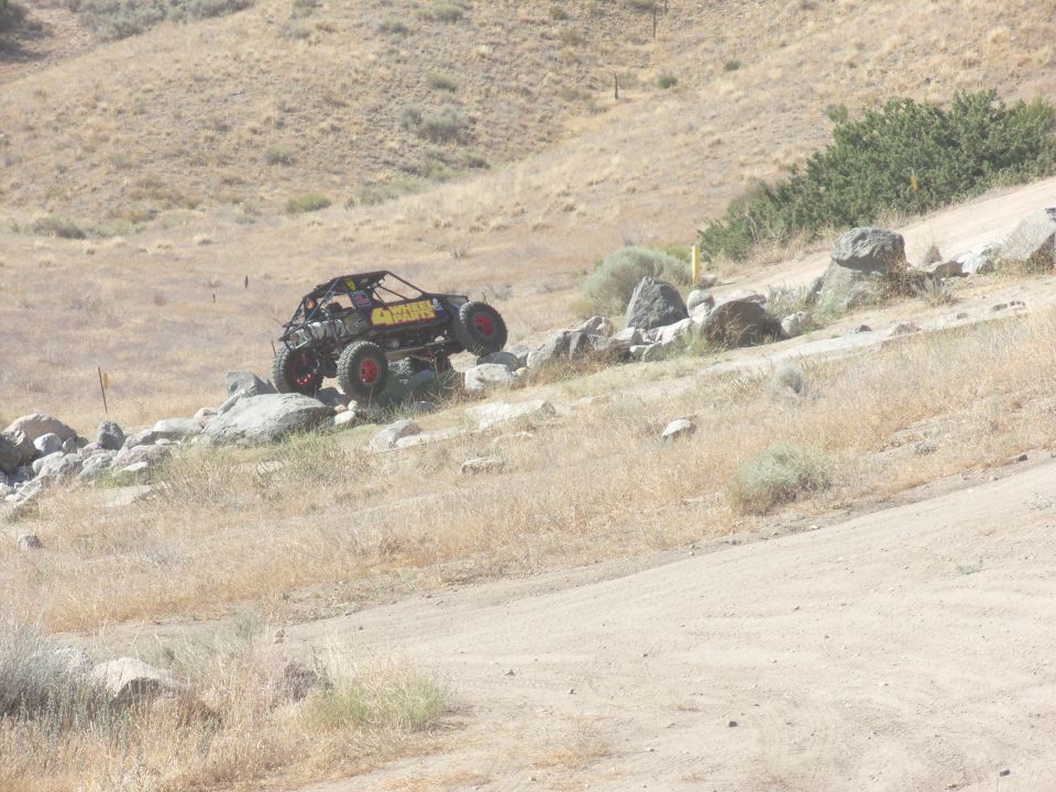 Off-road buggy with red wheels and yellow lettering on a rocky incline
