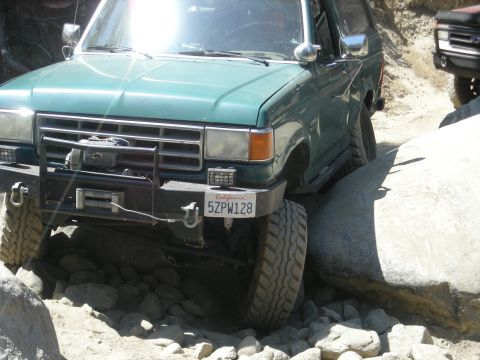 1991 Ford Bronco - This 1991 Ford Bronco navigates a rocky trail, with another vehicle partially visible in the background.