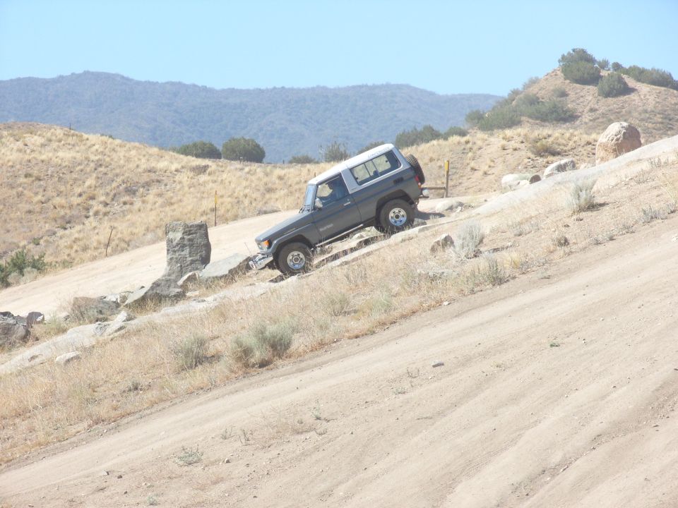Gray SUV with a white top on a rocky incline, front-left view