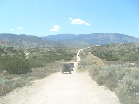 1995 Ford Bronco - A convoy of off-road vehicles travels down a remote dirt path in a mountainous, arid region.